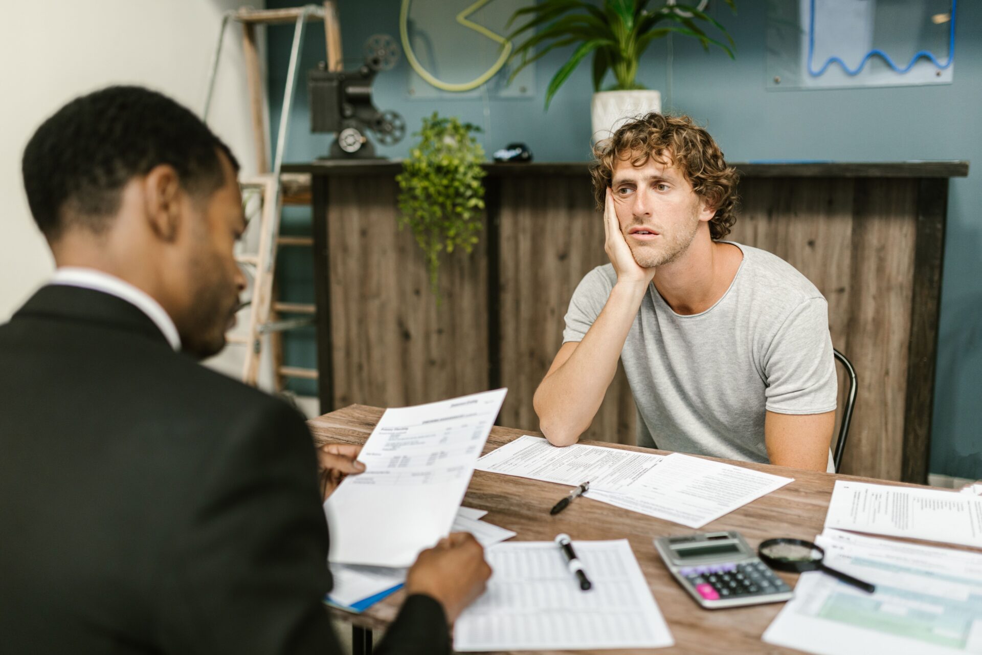 A stressed business owner reviewing financial documents with an advisor, illustrating the challenges of managing debt and the benefits of business debt consolidation for simplifying repayments and improving cash flow.