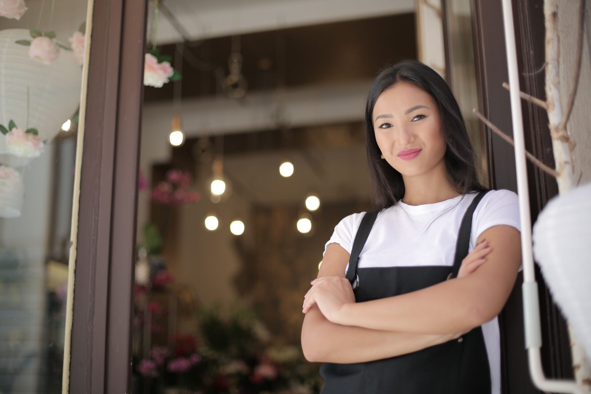 Woman standing in the doorway of a small business, representing access to business loans for immigrants.